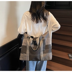 Detail of grey canvas tote bag with striped handles and adjustable shoulder strap