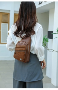 Detail view of brown PU leather crossbody chest bag with triple zipper design on model