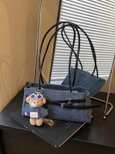 Minimalist blue denim baguette bag with black leather straps and a cute teddy bear charm