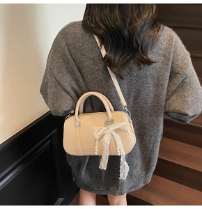 Beige pebble leather bowling bag detail with delicate white lace bow and pearl charm