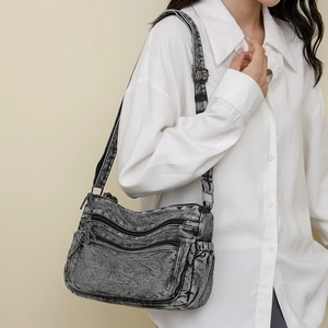 Vue latérale du sac bandoulière en denim délavé avec plusieurs compartiments zippés et sangle