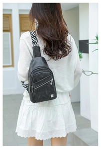 Detail of black faux leather chest bag with chic herringbone pattern woven strap