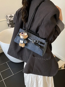 Blue denim underarm bag with black leather straps and a small bear charm detail