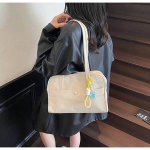 Dettaglio della borsa tote in tela bianco avorio con ciondolo a stella colorato e tracolla