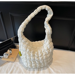 Detailed view of white quilted puffer bag with neon Fashion tag and top zipper closure