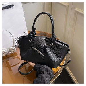 Detail of black lychee grain leather tote bag with knotted handles and silver metal hardware