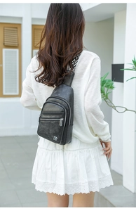 Outdoor shot of a black vintage texture chest bag with patterned strap on model's back