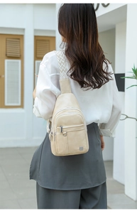 Cream white PU leather crossbody bag with multi-zipper pockets and woven strap on a model