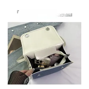 Top view of white leather and denim crossbody bag showing spacious interior with essentials