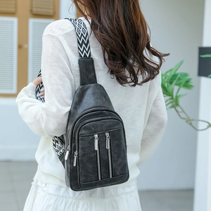 Detail of vintage black leather chest bag featuring geometric patterned woven strap