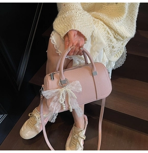 Pink lychee leather bowling bag with pearl lace bow charm shown in a lifestyle setting