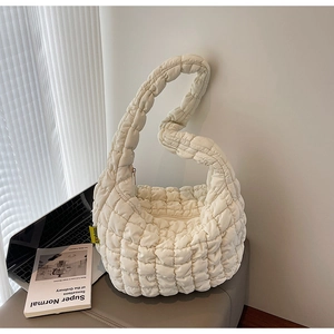 Detail of quilted cloud bag with fashion label on grey soft stool in home office setting