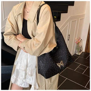Detail der modischen schwarzen Polka-Dot-Tasche mit goldenem Schmetterlingsanhänger
