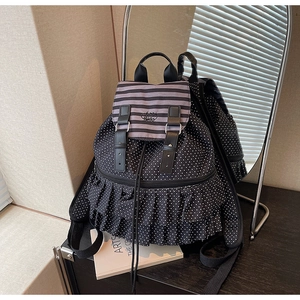 Detail of polka dot backpack featuring striped lid and ruffled trim in mirror reflection