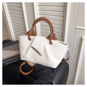 Detail of lychee pattern beige leather tote bag with brown knot handle and silver hardware