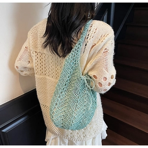 Detailed back view of a woman wearing a light green hollow-out knit tote bag
