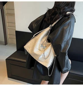 Détail du sac cabas en cuir blanc cassé avec chaînes argentées et breloque papillon perlé