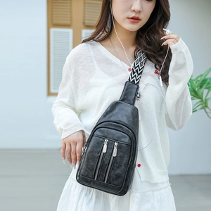 Close-up of black retro leather sling bag with dual zippers and woven shoulder strap