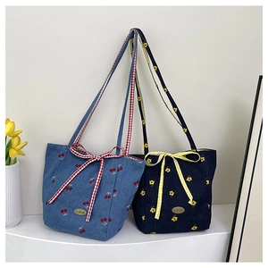 Detail of denim tote bags with cherry embroidery and checkered bow accents
