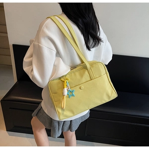 Dettaglio della borsa tote in tela gialla con ciondolo a stella e cinturino decorativo