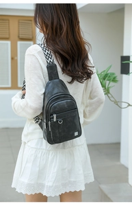 Fashionable black faux leather sling bag with geometric woven strap on female model