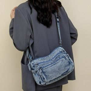 Vue détaillée du dos : sac bandoulière en denim bleu délavé avec plusieurs fermetures éclair