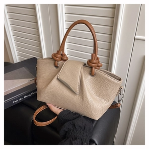 Detail of beige litchi grain leather tote with brown cylindrical knot handles and strap