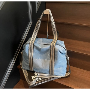 Detailed blue denim tote bag with striped woven handles on a wooden staircase