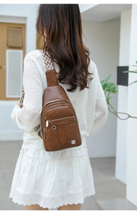 Detail view of brown vintage PU leather chest bag with a striped woven shoulder strap