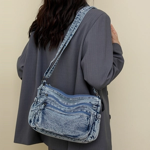 Détail du sac bandoulière en denim bleu délavé avec poches zippées et style rétro