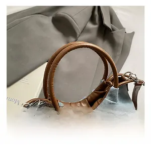Detail of light blue denim texture bag with brown leather handle and pleated design