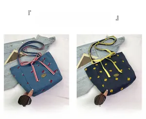 Detail of denim tote bags with cherry and flower embroidery and plaid bow closure