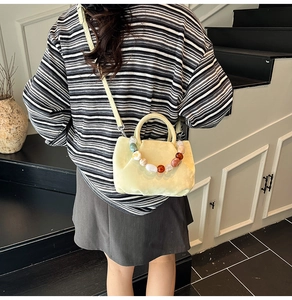 Détail d'un sac seau plissé beige avec chaîne en résine et poignée en similicuir