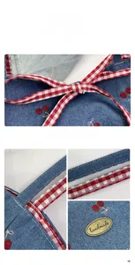 Detail of blue denim tote bag with cherry embroidery and handmade metal label