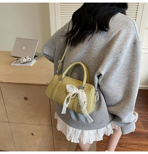 Detailed shot of a green mini Boston bag with white lace bow and pearl chain decoration