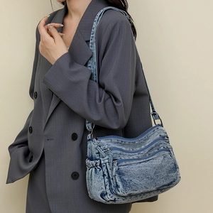 Détail du sac en denim avec plusieurs poches zippées et texture vintage délavée