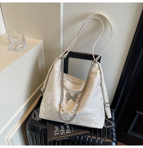 Détail du sac à main en jacquard blanc avec breloques papillon argentées et perles