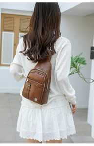 Rear view of brown faux leather chest bag with multiple silver zipper pockets on white outfit