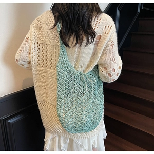 Detail of light green hollow-out crochet tote bag with wave knit texture and shoulder strap