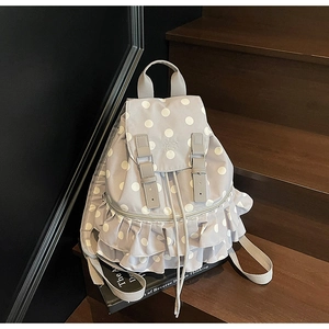 Detail of grey polka dot backpack featuring sweet ruffle trim and drawstring closure