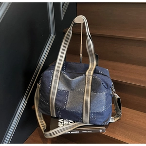Detail of large denim patchwork tote with striped handles and adjustable shoulder strap