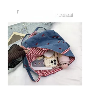 Detail of blue denim tote bag with cherry embroidery showing large interior storage space