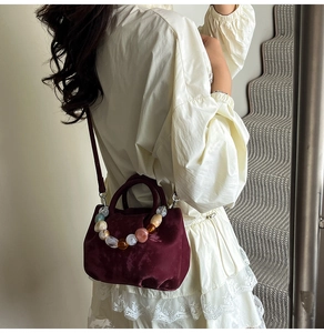 Détail du sac seau en velours bordeaux avec poignée en perles et bandoulière