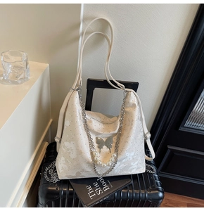 Détail du sac blanc perlé avec chaîne papillon argentée et grandes perles décoratives