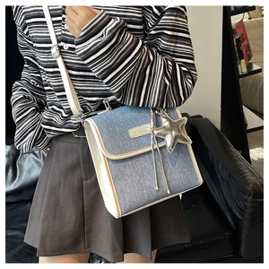 Detail of blue denim shoulder bag with white leather trim and silver star charm pendant