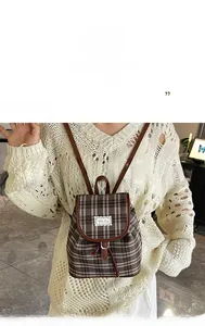 Detail of British style checkered canvas backpack with brown leather trim and drawstring