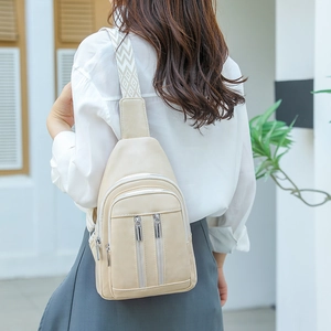 Beige leather chest bag detail with double zippers and geometric woven shoulder strap