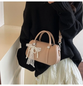 Detail of apricot Boston bag showing lychee grain texture and pearl lace bow accessory