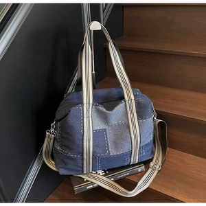 Detail of checkered denim patchwork tote bag with contrast stitching and striped strap