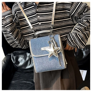 Detail of blue denim shoulder bag with silver leather trim and metal star charm